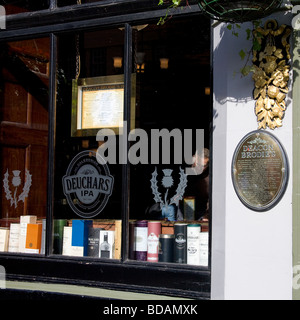 Un uomo visto attraverso una finestra, naviga in marchi di whisky in Deacon Brodies nell'Edinburgh Royal Mile. Foto Stock