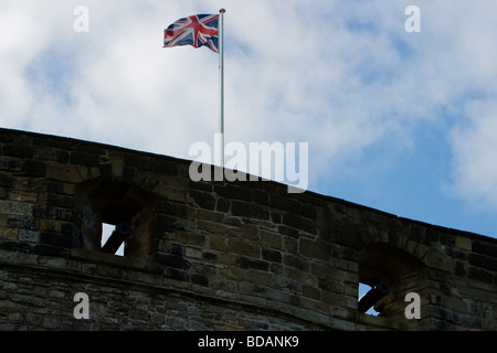 La Union Jack sventola bandiera oltre i bastioni del Castello di Edinburgo Foto Stock