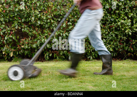 Un ecologico uomo utilizzando un tosaerba da spinta per falciare l'erba del prato Foto Stock