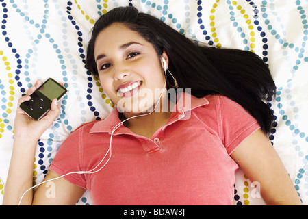 Ritratto di una giovane donna di ascolto di un lettore mp3 e sorridente Foto Stock