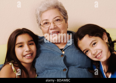 Ritratto di un senior donna seduta con i suoi due nipoti e sorridente Foto Stock