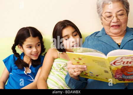 Close-up di un senior donna seduta con i suoi due nipoti e la lettura di un libro di fotografia Foto Stock