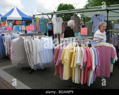 Gli anziani gli acquisti in un affare di stallo vestiti Chichester tradizionale mercato West Sussex Foto Stock