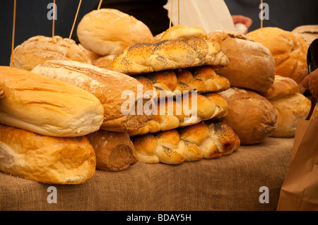 Pane fresco artigianale impilato su una bancarella di mercato. Panetteria rustica con baguette e rotoli croccanti. Foto Stock