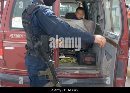 Come un giovane ragazzo si affaccia sulla polizia federale per controllare le forze di automobili per armi e droga in corrispondenza di un punto di controllo in una strada a Ciudad Juarez Foto Stock