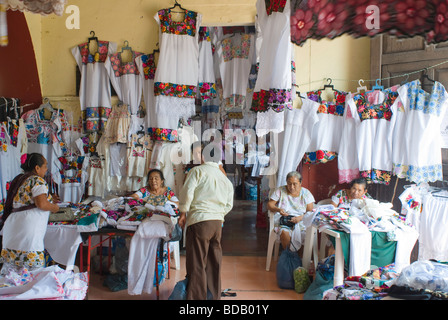 Donne ricamare e vendere abiti tipici degli indigeni di Maya nella penisola dello Yucatan in un mercato della città di Valladolid. Foto Stock