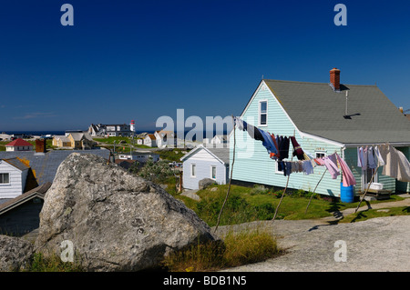 Pesca rurale case di villaggio intorno a rocce con lavanderia su stendibiancheria e il faro di Peggy;s Cove Nova Scotia sull'Oceano Atlantico Foto Stock