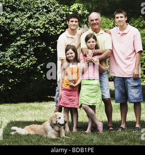 Senior uomo in piedi con i nipoti e un cane in un parco Foto Stock