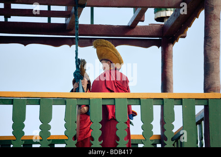 I giovani monaci buddisti clang un cerimoniale di cembalo in una torre in monastero Gandan, ad Ulaan Baatar, Mongolia Foto Stock