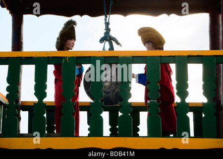 I giovani monaci buddisti clang un cerimoniale di cembalo in una torre in monastero Gandan, ad Ulaan Baatar, Mongolia Foto Stock