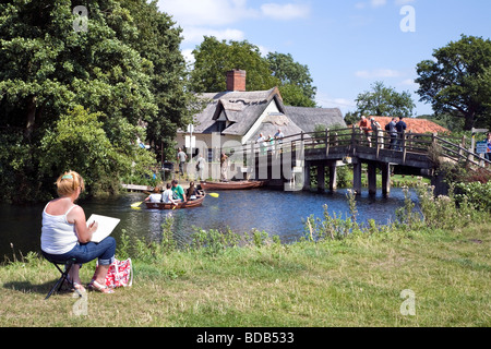 Una donna delineando la scena al cottage di ponte sul fiume Stour a Flatford in Constable Country. Foto Stock