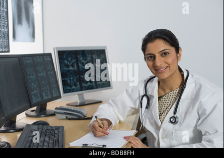 Medico donna scrivendo una prescrizione e sorridente Foto Stock