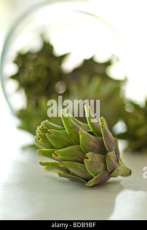 Studio ancora in vita di carciofi crudi in una ciotola di vetro sul tasto alto sfondo bianco Foto Stock