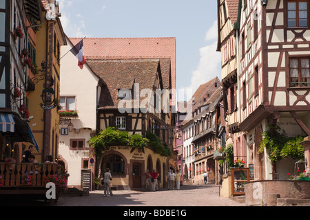 Riquewihr Alsace Haut Rhin Francia Street scene con vecchi edifici con travi di legno nella pittoresca cittadina medievale sul vino Alsaziano rotta Foto Stock