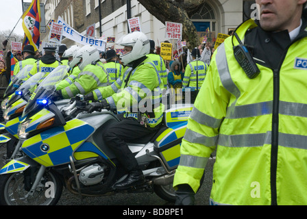 Motociclisti di polizia di fronte Pro-Tibet manifestanti come Pechino fiamma olimpica è portato attraverso Londra Foto Stock