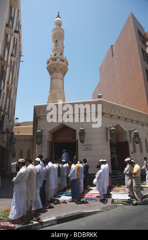 Invito alla preghiera in Dubai. Centinaia di uomini in preghiera nelle strade al di fuori del pranzo moschee. Foto Stock