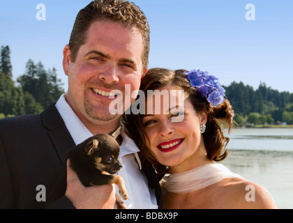La sposa e lo sposo posano con il loro Chihuahua messicano di fronte lago Capitol in Olympia, Washington. Foto Stock