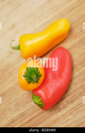 Colorato Sweet baby peperoni peperoni disposti su un tagliere di legno Foto Stock