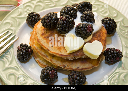 Tutto sano frittelle di grano condito con yogurt di more e a forma di cuore sul burro una bella piastra. Foto Stock