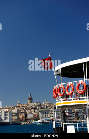 Una vista attraverso il Golden Horn verso la Torre di Galata a Istanbul con un traghetto in primo piano. Foto Stock
