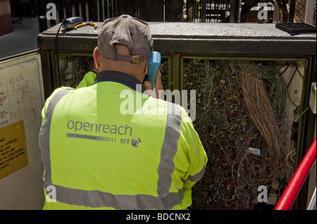 Guardando sopra la spalla di British Telecom BT Outreach ingegnere di lavoro sul telefono infront di scambio aperto / cablaggio scatola di connessione Foto Stock