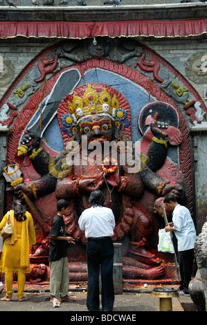 Nero Bhairab statua e fedeli pregano offerta rituale del culto Khal Bhairav Shiva il quadrato di Durbar Kathmandu in Nepal Foto Stock