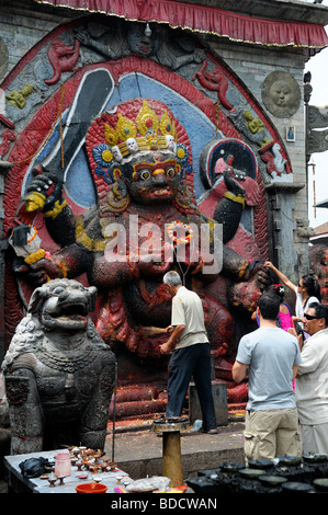 Nero Bhairab statua e fedeli pregano offerta rituale del culto Khal Bhairav Shiva il quadrato di Durbar Kathmandu in Nepal Foto Stock