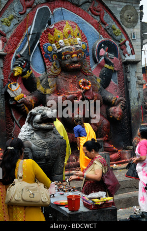 Nero Bhairab statua e fedeli pregano offerta rituale del culto Khal Bhairav Shiva il quadrato di Durbar Kathmandu in Nepal Foto Stock