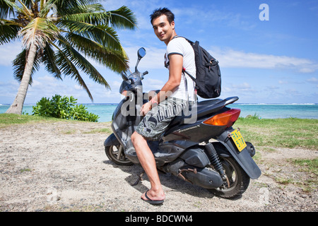 Giovane uomo seduto su un affittato uno scooter da spiaggia Foto Stock