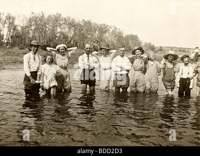 Completamente vestito gruppo guadare in fiume Foto Stock