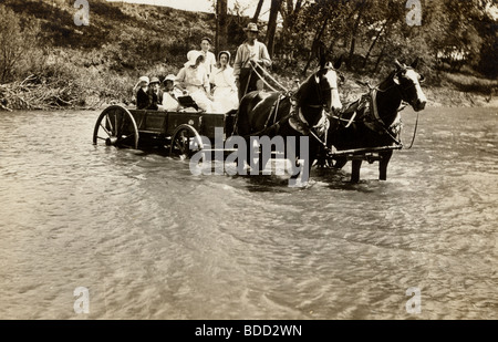 Famiglia a cavallo carro guadare il fiume Foto Stock