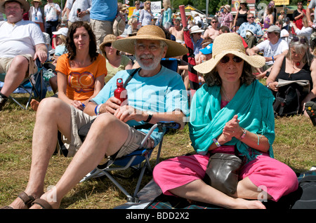 Due seguaci di musica di mezza età seduti su sedie da campeggio tra la folla al festival musicale WOMAD Foto Stock