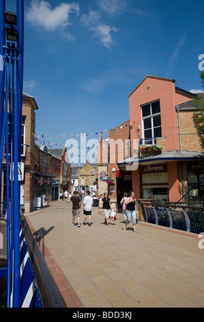 La gente a piedi attraverso una zona pedonale nella graziosa cittadina di mercato di Market Harborough, Leicestershire Foto Stock