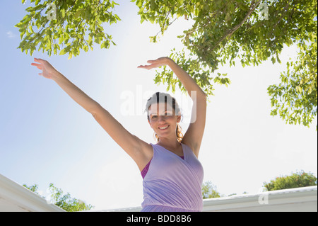 Donna in piedi con le braccia sollevate Foto Stock