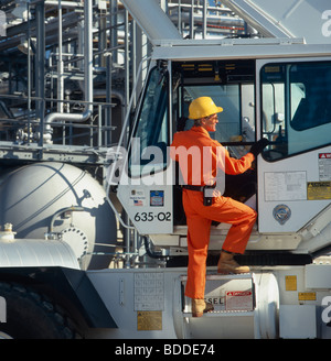 Lavoratore di sesso maschile in tuta arancione arrampicata in un camion in un impianto industriale. Foto Stock