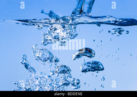 Versare acqua creando bolle sotto la superficie Foto Stock