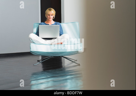 Donna che utilizza un computer portatile su un lettino Foto Stock