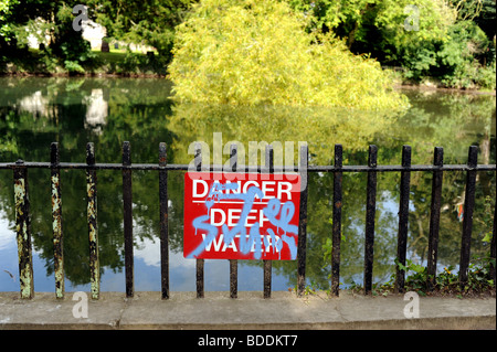 Cartello di pericolo acqua profonda ricoperto di graffiti nello stagno di Stanmer Park Brighton Sussex Regno Unito Foto Stock