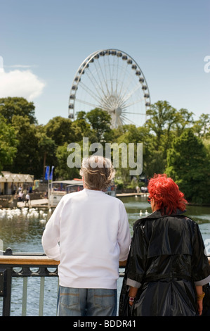 Due persone che guardano il Royal Windsor ruota gigante da Eton e Windsor ponte sopra il fiume Tamigi Foto Stock