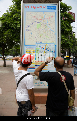 Due uomini indiano guarda un percorso informazioni mappa della metropolitana di Delhi sistema sul display esterno Rajiv Chowk stazione. Delhi, India. Foto Stock