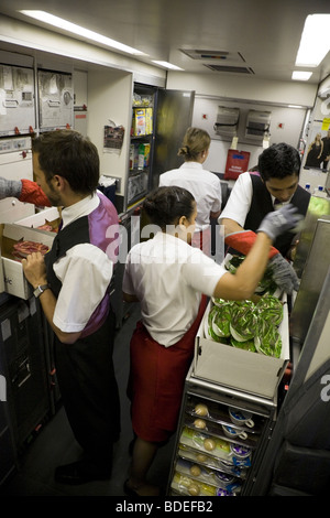 I membri di equipaggio di cabina preparare per servire i pasti nella cucina di bordo di un Virgin Atlantic aeromobile durante la fase di Mumbai a Londra volo. Foto Stock
