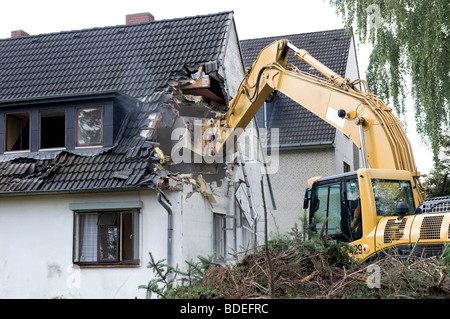 Un escavatore la demolizione di case per la ricostruzione. Foto Stock