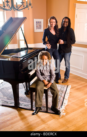 Interracial famiglia riunita attorno al pianoforte Foto Stock