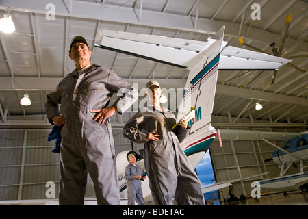 Tre aereo meccanica in hangar in piedi dal jet privato Foto Stock