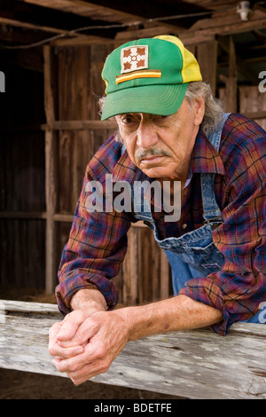 Ritratto di senior uomo che indossa cappuccio verde appoggiato sulla recinzione di legno Foto Stock