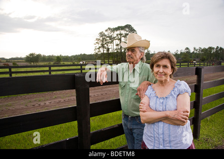 Coppia senior in piedi sul ranch vicino al recinto Foto Stock