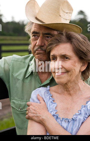 Close-up di coppia senior in piedi sul ranch vicino al recinto Foto Stock