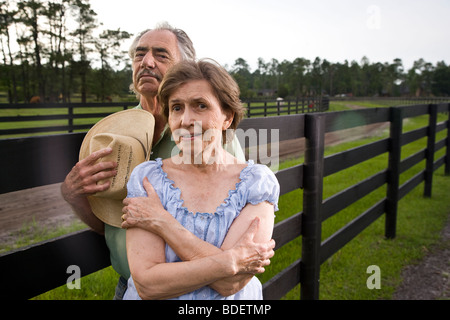 Coppia senior in piedi sul ranch vicino al recinto Foto Stock