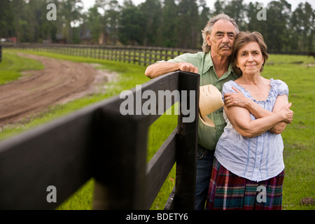 Coppia senior in piedi sul ranch vicino al recinto Foto Stock