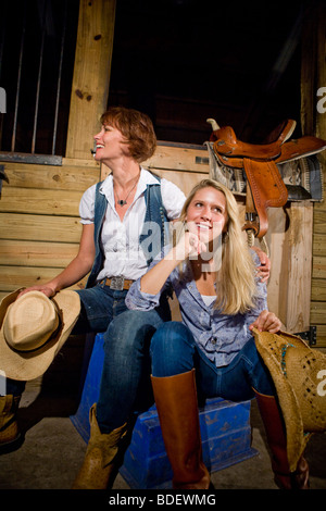 Madre e figlia adolescente indossando scarpe e cappello da cowboy a cavallo stabile Foto Stock